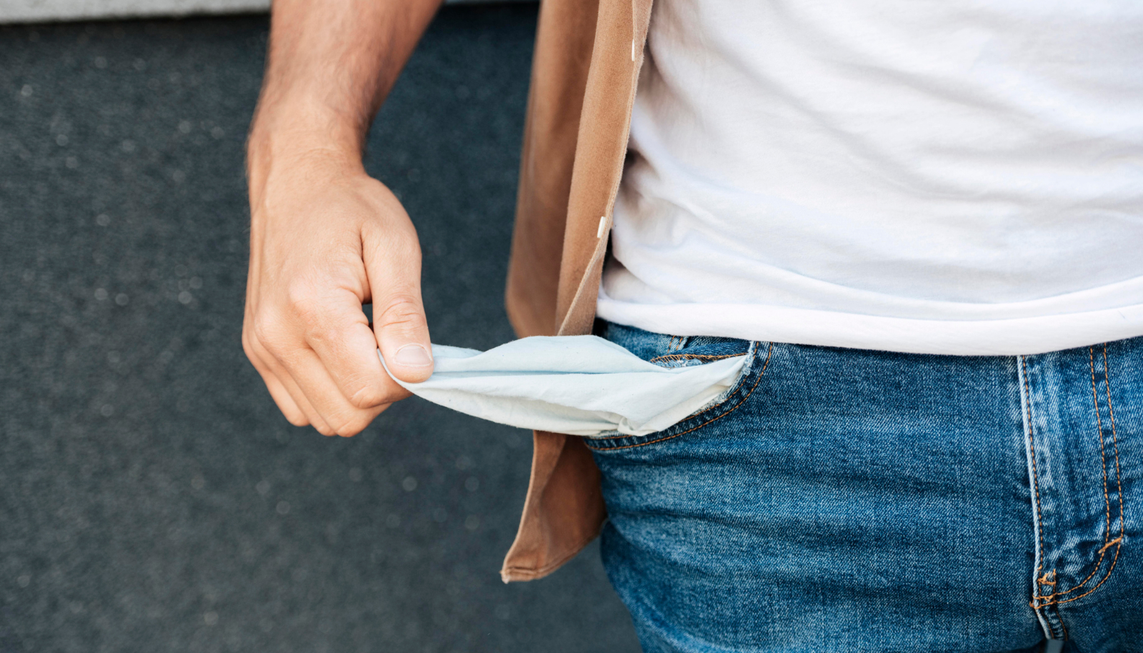 persona con los bolsillos fuera del pantalón demostrando que no tiene dinero